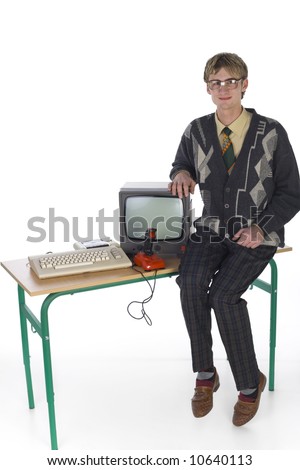 Nerdy man sitting on table next to old-fashioned computer. Smiling and looking at camera. Front view, white background. Whole body