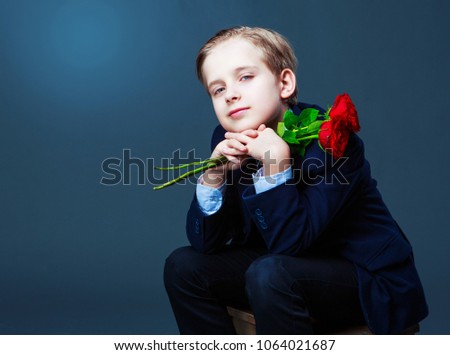 hansome boy wearing a black suit with roses in his hands, isolated against studio background