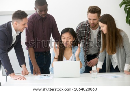 Serious multiracial millennial team solving online problem together, diverse focused asian, african and caucasian colleagues discuss project brainstorming working on laptop, creative office teamwork Royalty-Free Stock Photo #1064028860