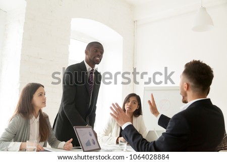 Rude angry african businessman arguing shouting at colleague at team meeting, mad black employee showing bad behavior hate disrespect at group negotiations, harassment, humiliation and discrimination Royalty-Free Stock Photo #1064028884