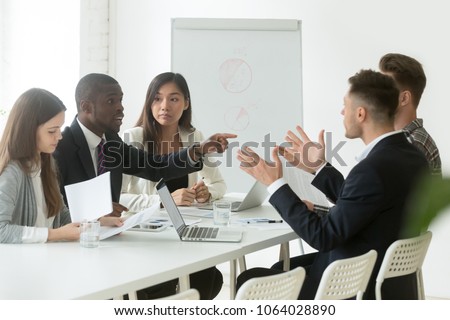 Diverse employees arguing during team meeting, african office worker disagreeing with caucasian colleague, black and white businessmen disputing at negotiations, multiracial conflict at work concept Royalty-Free Stock Photo #1064028890