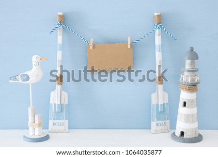 nautical concept with hanging note message on a string next to lighthouse and seagull over blue background