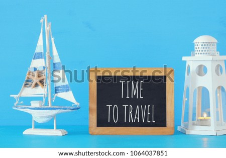 nautical concept with white decorative wooden boat and lighthouse lantern next to blackboard space over blue background