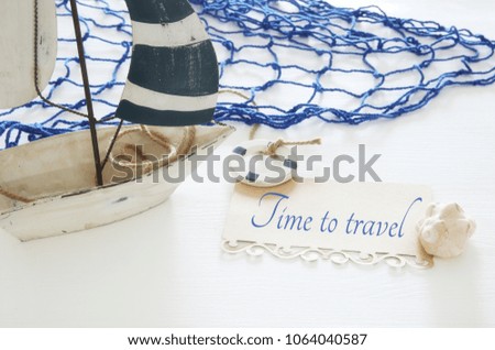 nautical concept image with white decorative sail boat and note over white wooden table