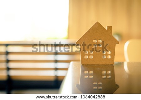 Concept of hard paper house on wood table with reflection, a symbol for construction , ecology, loan, mortgage, property or home.