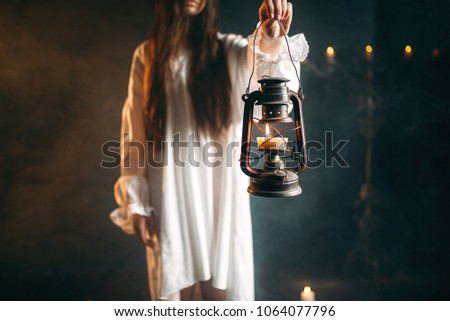 Female person holds kerosene lamp, dark magic