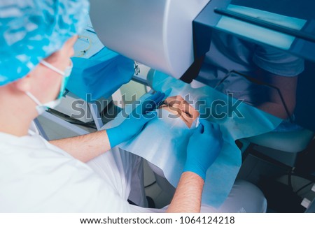 Laser vision correction. A patient and team of surgeons in the operating room during ophthalmic surgery. Eyelid speculum. Lasik treatment. Patient under sterile cover Royalty-Free Stock Photo #1064124218