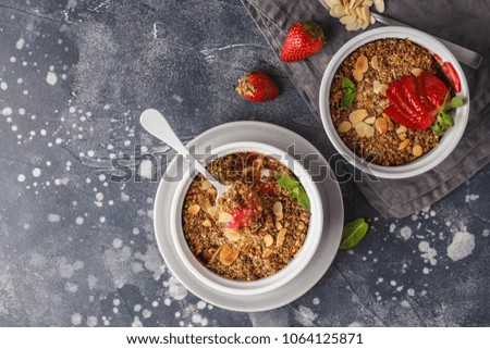 Homemade breakfast strawberry crumble. Mini berry cake with strawberry, dark background. Healthy vegan food concept.