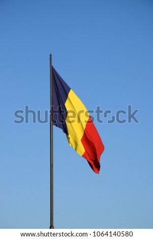 Romanian flag waving in the wind in front of a clean blue sky. Romania National Flag.