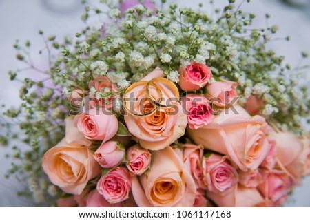 Bridal bouquet with orange and pink roses of different size with handle on white background.