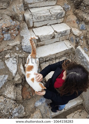 picture from above of a girl playing with a cat in Ephesus ruins, Turkey