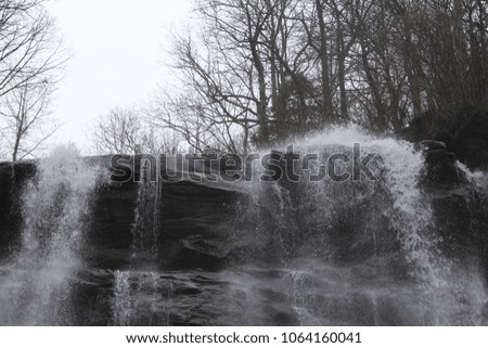 Waterfall horizon with trees and gray sky in background.