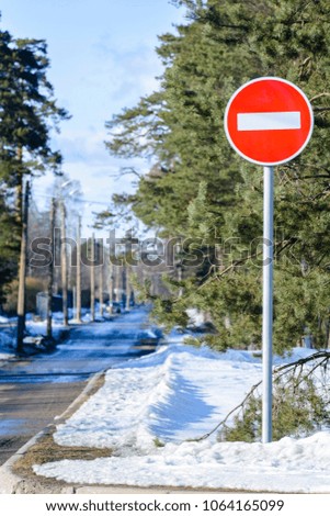 No entry for vehicles traffic - red stop road sign on a spring suburban road, there is still snow on the roadside