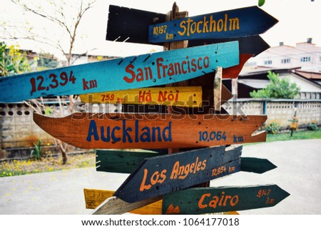 Handmade wooden sign with names of cities and distance at hostel for backpackers.