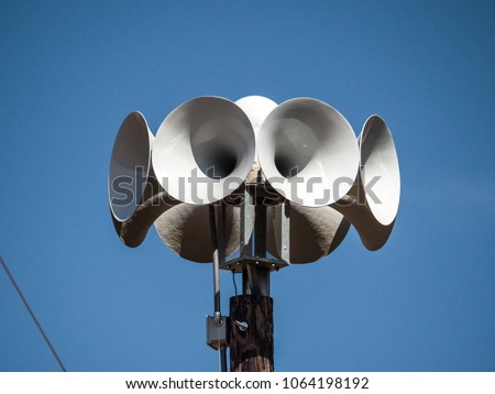 Close up photograph of several multi directional round amplified emergency siren  or noon time horns on top of a wooden pole in a small town in Wisconsin. Royalty-Free Stock Photo #1064198192