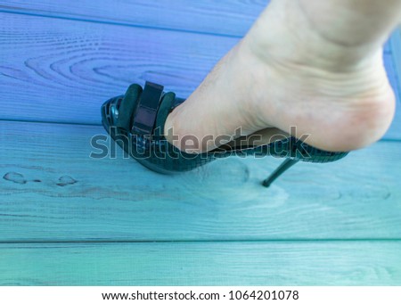 A man's leg in a woman's shoe with a heel. The concept of inappropriate shoe size, orientation disorders. Royalty-Free Stock Photo #1064201078