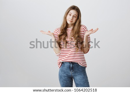 I do not care about rules. Portrait of indifferent careless teenage girl with blonde hair shrugging and holding spread palms near shoulders, being uninterested and bothered with stupid questions Royalty-Free Stock Photo #1064202518