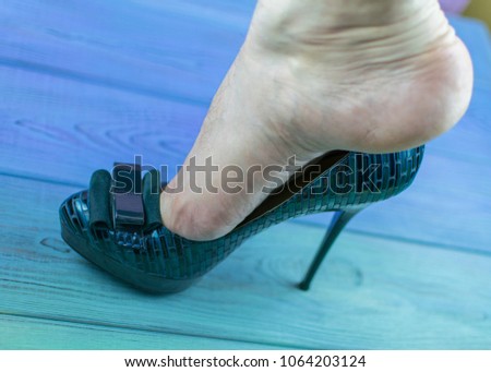 A man's leg in a woman's shoe with a heel. The concept of inappropriate shoe size, orientation disorders. Royalty-Free Stock Photo #1064203124