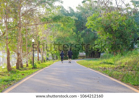 A front selective picture of a green natural park with a jogging couple at background 