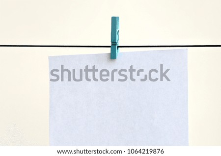 White blank cards on rope, light wall background. Creative reminder, small sheets of paper on old clothespin, memo backdrop