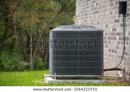 HVAC Air Conditioning Unit on concrete slap with new construction brick house Royalty-Free Stock Photo #1064221910