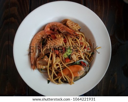 Sea turtle spaketti with squid shirmp and big mussel in hot and spicy sauce of basil and chili  in white dish for surving meal.