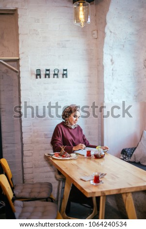 muslim woman working in cafe, writing on notepad