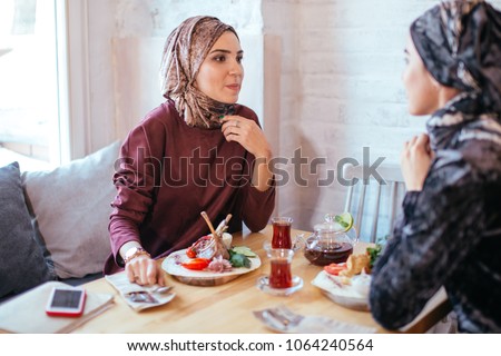 Two pretty Muslim women in cafe, friends meeting