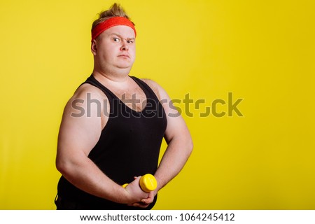 fat man wearing black shirt exercising with dumbbells and looking at camera