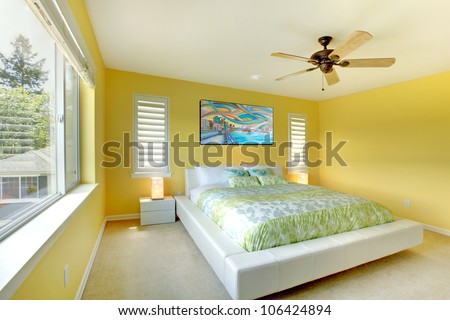 Yellow bright bedroom with green bedding and white bed.