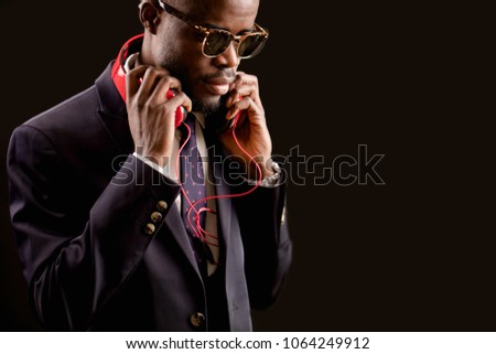 close up cropped side view image of man in formal clothes with red headphones on his neck. seductive music.