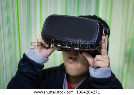 Asian boy wearing a black VR, showing stunned gesture with what to see.