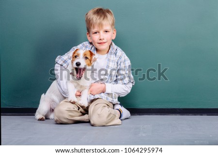 Seria emotional photo portrait of cute preschooler baby boy playing, hugging and strokes a puppy jack russel terrier dog indoor over green wall background.
