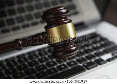Law legal concept photo of gavel on computer with legal books in background.