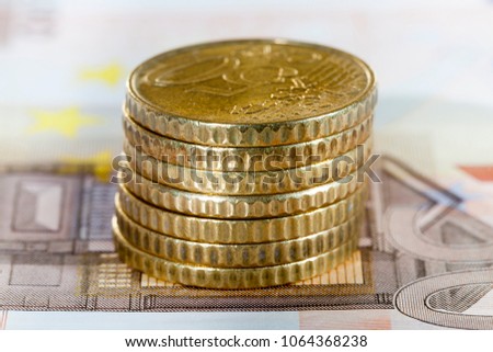 a stack of European coins of fifty euros, lying on a banknote of ten euros, a closeup photo of cash