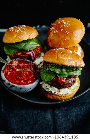 Burgers with grilled beef patties, cream cheese and spinach on classical bun. Dark rustic wooden background