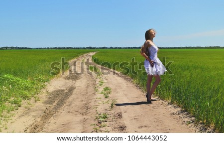 On the road among fields is a young girl