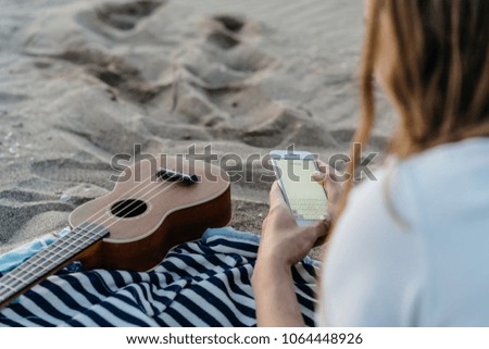 young pretty hipster girl using white smart phone at the beach/ space for your text