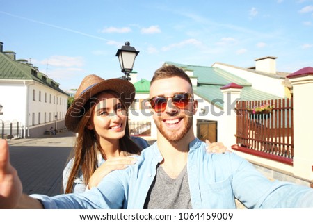 Happy couple of tourists taking selfie in old city.
