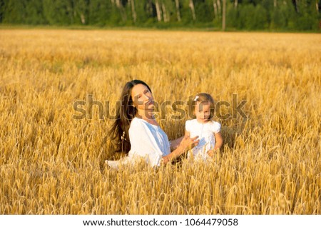 Mom and daughter walking in the grain fields