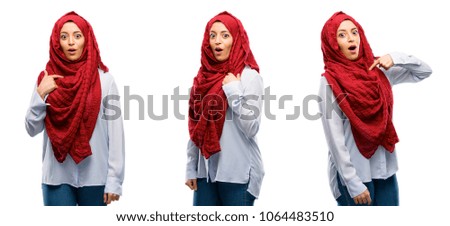 Arab woman wearing hijab happy and surprised cheering expressing wow gesture, pointing with finger isolated over white background