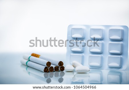 Nicotine chewing gum in blister pack near pile of cigarette. Quit smoking by use nicotine gum for relief of nicotine withdrawal symptoms. Medicine for giving up smoking. World no tobacco day concept. Royalty-Free Stock Photo #1064504966
