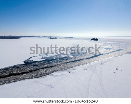 Aerial view of the water area of the Gulf of Finland with fishermen on the ice near Kronstadt. Russia, the Baltic Sea