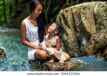 asian happy mother with her daughter in the tropics near the waterfall. Mothers day.