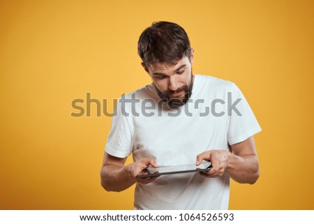   man in a white T-shirt with a beard looking at the tablet                             