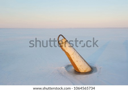 A buoy stuck in a frozen river. 
Beautiful 'pinkish' horizon.
Untouched white snow covering the ice. 