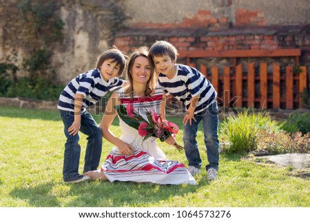 Cute little boy, giving present to his mom for Mothers day in the garden
