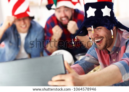 Picture of happy male friends cheering and watching sports on tv