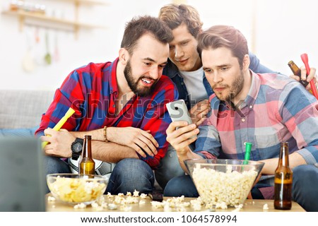 Picture of happy male friends cheering and watching sports on tv
