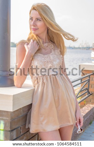 Young beautiful blond woman in a beautiful dress on the waterfront